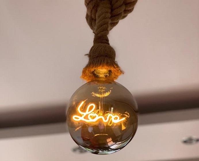 Moderná žiarovka so svetelným nápisom Love zavesená na lane